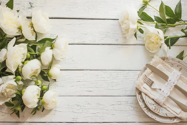 Sofra ve gümüş beyaz ahşap kurullarında beyaz peonies bir buket
