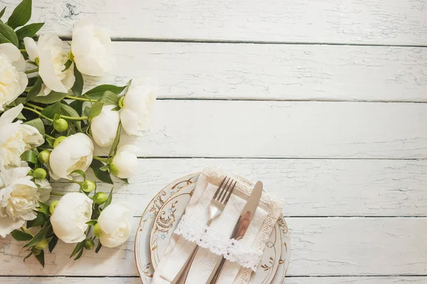 Sofra ve gümüş beyaz ahşap kurullarında beyaz peonies bir buket