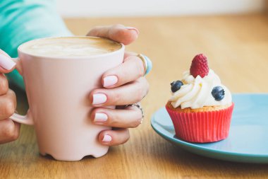 Bir fincan kahve ve çörek plaka ile kadının el