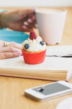 Fincan kapuçino, cupcake ve bir kitap ile bir telefon