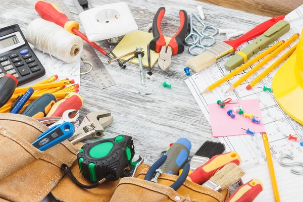 Desenhos, capacete amarelo e uma correia de construção com diferentes ferramentas de construção — Fotografia de Stock