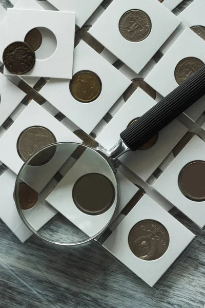 Different collector's coins with a magnifying glass and money bag, soft focus background — Stock Photo, Image