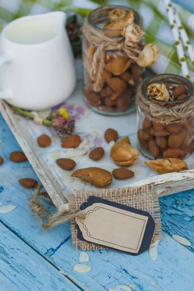 Mandel i glas, burk med mjölk på träbricka och dekorativa tagg — Stockfoto