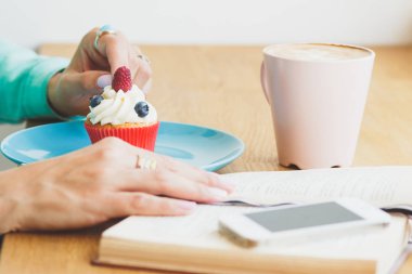 Fincan kapuçino, cupcake plaka ve bir kitap ile bir telefon ile