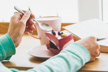 Bir fincan kapuçino ve tatlı plaka üzerinde bir parçası olan kadın