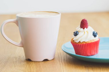 Ahududu ve tabakta sıcak cappuccino bardak yaban mersini ile küçük cupcake