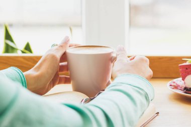 Plaka ve sıcak içecek bir fincan ile kadının el Cheesecake