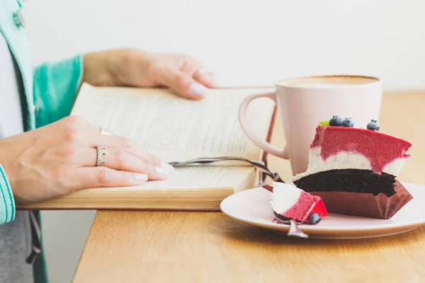 Femme avec une tasse de cappuccino et un morceau de dessert dans l'assiette — Photo