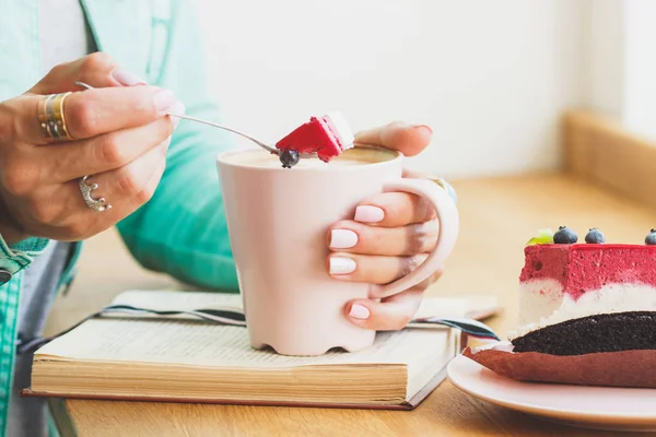 Cheesecake sur l'assiette et les mains de la femme avec une tasse de boisson chaude — Photo