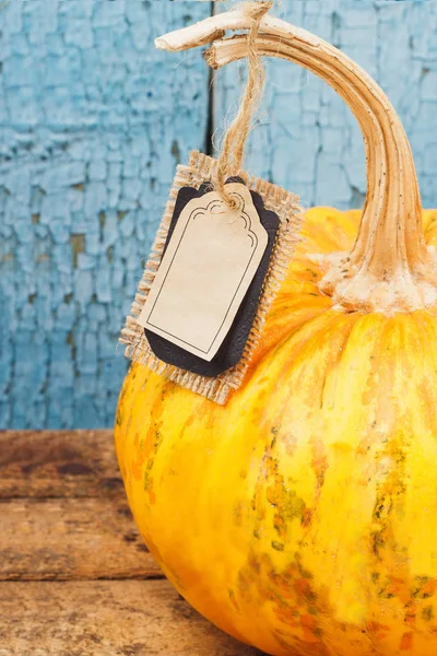 Calabaza naranja con etiqueta decorativa, fondo de madera — Foto de Stock