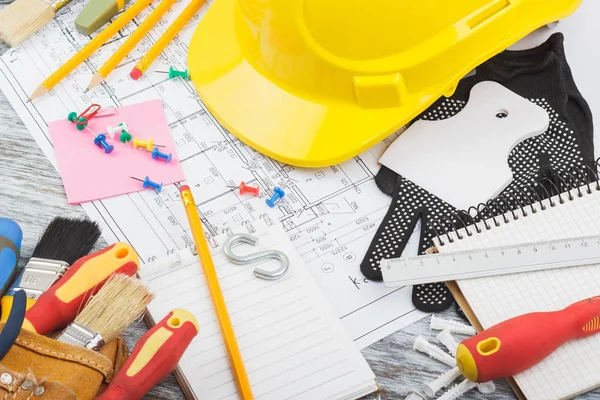 Desenhos, capacete amarelo e uma correia de construção com diferentes ferramentas de construção — Fotografia de Stock
