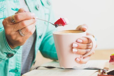 Bir fincan kapuçino ve tatlı plaka üzerinde bir parçası olan kadın