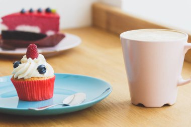 Ahududu ve tabakta sıcak cappuccino bardak yaban mersini ile küçük cupcake