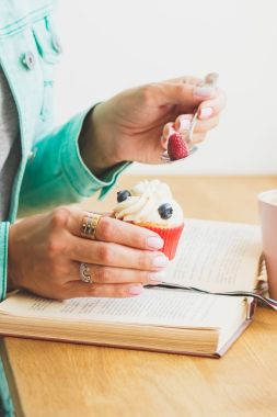 Ahududu ve yaban mersini, kitap ve fincan sıcak cappuccino küçük cupcake