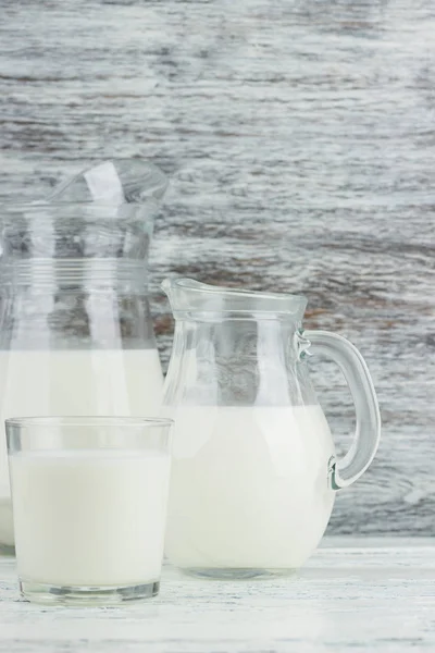 Milk in the glass jugs, white wooden background — Stock Photo, Image