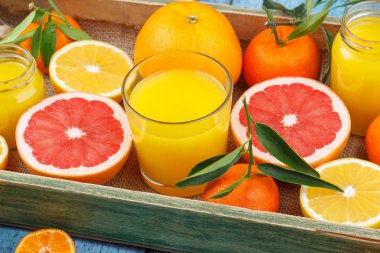 Farklı meyve ve taze portakal suyu, ahşap arka plan ile cam