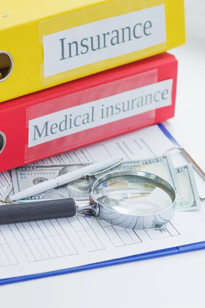 Ren försäkringsformulär, mappar, förstoringsglas, penna och pengar — Stockfoto