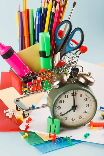 Carro de compras con diferentes artículos de papelería, fondo azul claro — Foto de Stock