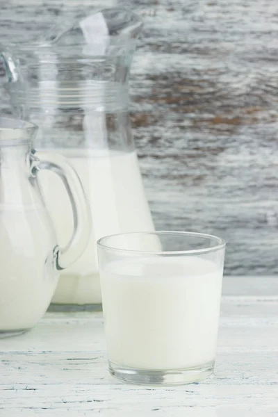 Milk in the glass jugs, white wooden background — Stock Photo, Image