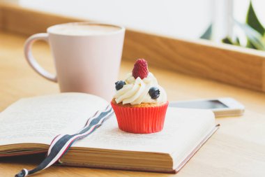 Ahududu, yaban mersini ve bir fincan sıcak cappuccino küçük cupcake