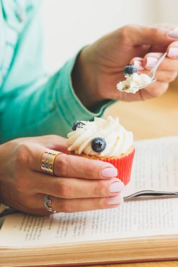 Ahududu ve yaban mersini, kitap ve fincan sıcak cappuccino küçük cupcake