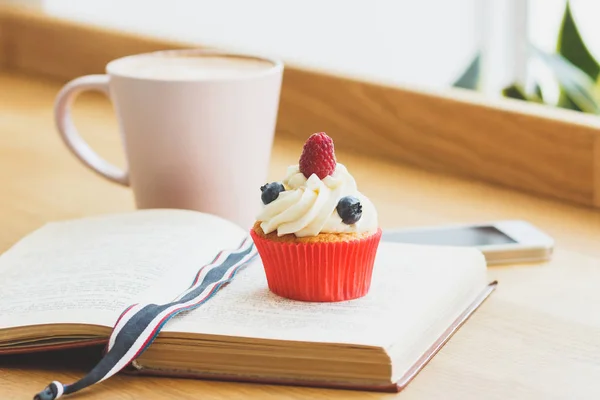 Petit cupcake aux framboises et bleuets et une tasse de cappuccino chaud — Photo