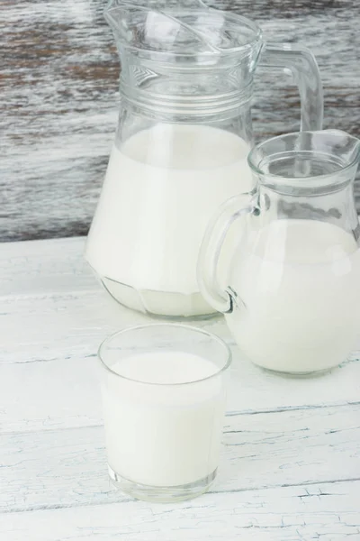 Milk in the glass jugs on the wooden background — Stock Photo, Image