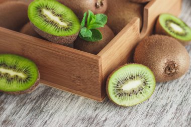 Yeşil kivi ve nane yaprakları içinde ahşap tepsi