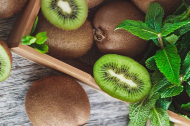 Yeşil kivi ve nane yaprakları içinde ahşap tepsi