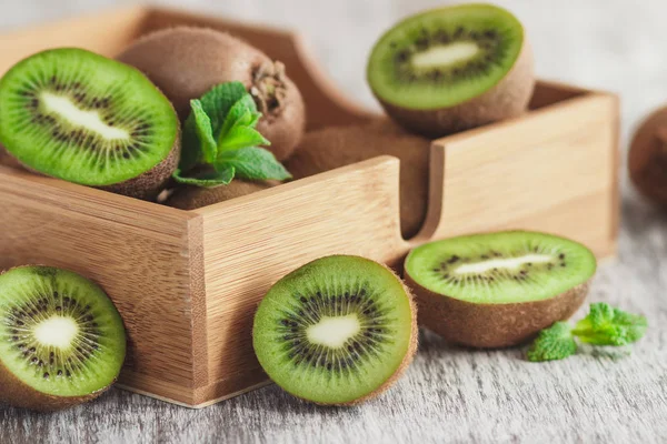 Kiwis verdes y hojas de menta en la bandeja de madera — Foto de Stock