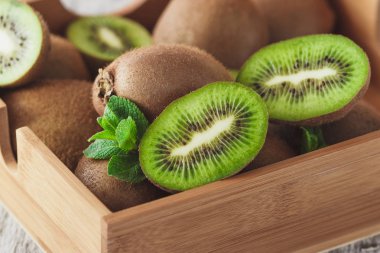 Yeşil kivi ve nane yaprakları içinde ahşap tepsi