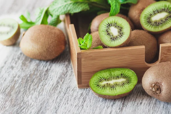 stock image Green kiwis and mint leaves in the wooden tray