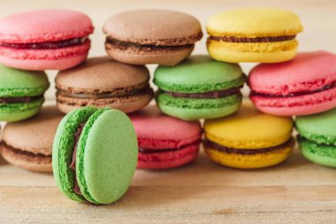 Yeşil, pembe, sarı ve kahverengi Fransız macarons ahşap kurullarında