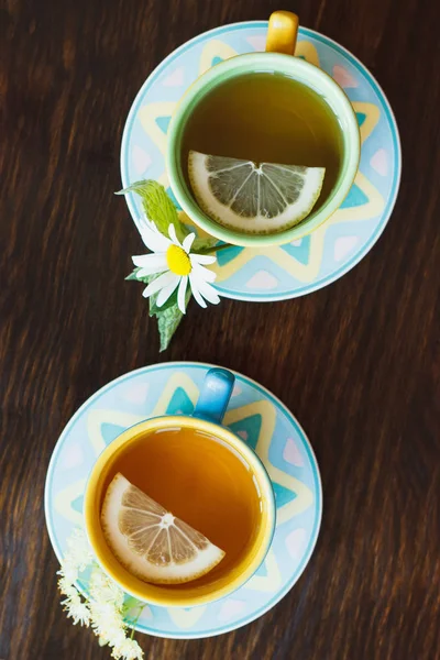 Cups with herbal tea, lemon, mint leaves and different herbs