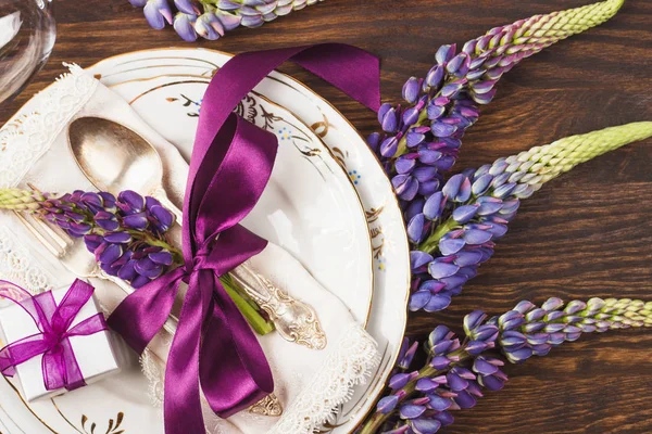 Tableware with violet lupines and silverware — Stock Photo, Image