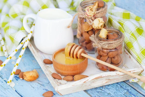Honung i trä skålen, mandel och burk med mjölk i trä facket — Stockfoto