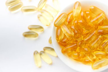 Dietary supplementation. Capsules of fish oil in the white bowl, light background clipart
