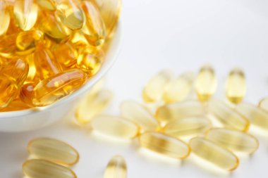 Beslenme takviyesi. Beyaz kasede balık yağı kapsülleri, açık arkaplan