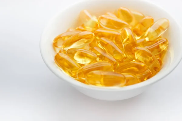 Dietary supplementation. Capsules of fish oil in the white bowl, light background — Stock Photo, Image