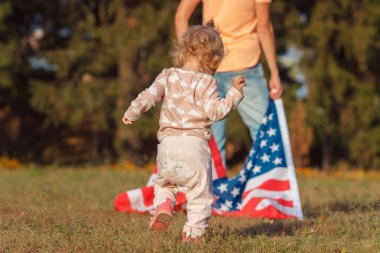 Küçük bir çocuk ve elinde Amerika Birleşik Devletleri bayrağı olan bir kadın.