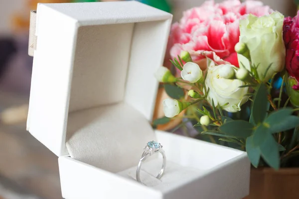 Silver ring and a bouquet of flowers, blurred background