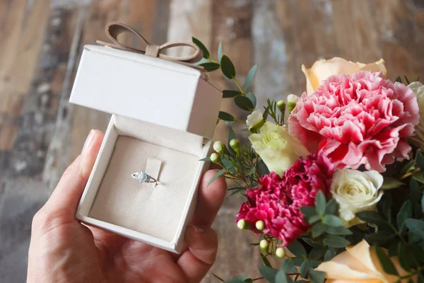 Anel de prata na mão e um buquê de flores — Fotografia de Stock