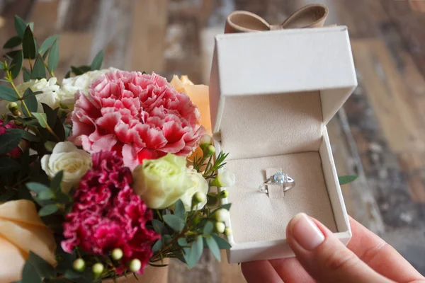 Anel de prata na mão e um buquê de flores — Fotografia de Stock