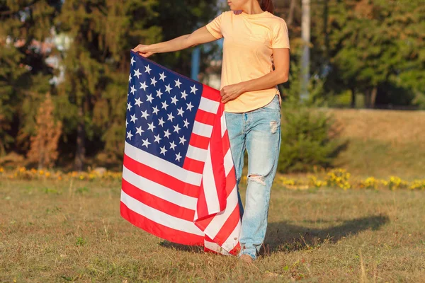 アメリカの国旗を手にした女性アウトドアソフトフォーカスの背景 — ストック写真