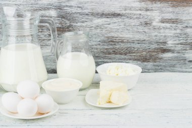 Beyaz tahta tahtalarda farklı süt ürünleri, bulanık arka plan.