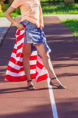 Ellerinde Amerika Birleşik Devletleri bayrağı olan bir kadın, açık havada, yumuşak odaklı arka planda