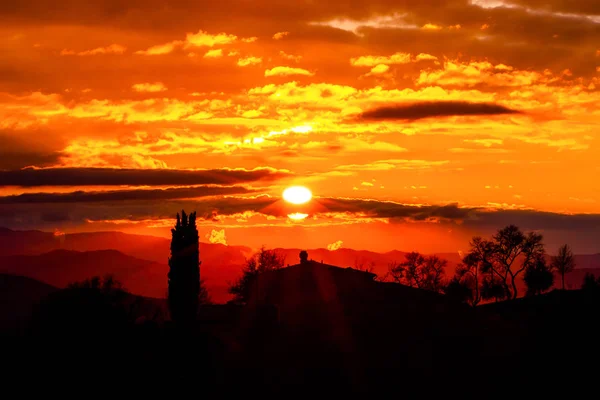 Tuscany landscape with red sun setting behind dark clouds and si — Stock Photo, Image