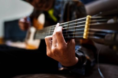 Odada gitar çalıyor.