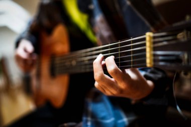 Odada gitar çalıyor.