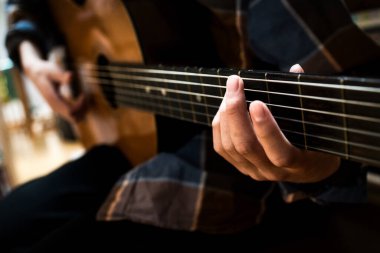 Odada gitar çalıyor.